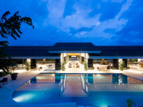 The image shows a luxurious poolside view at night with a modern building and glowing lights creating a serene atmosphere.