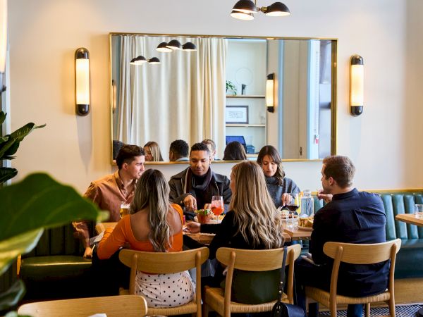 A group of people are enjoying a meal together around a table in a cozy restaurant setting.