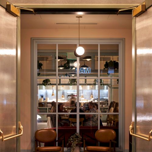 Entrance to a place named Local Jones, featuring double doors, warm lighting, and two chairs with a view of the interior.